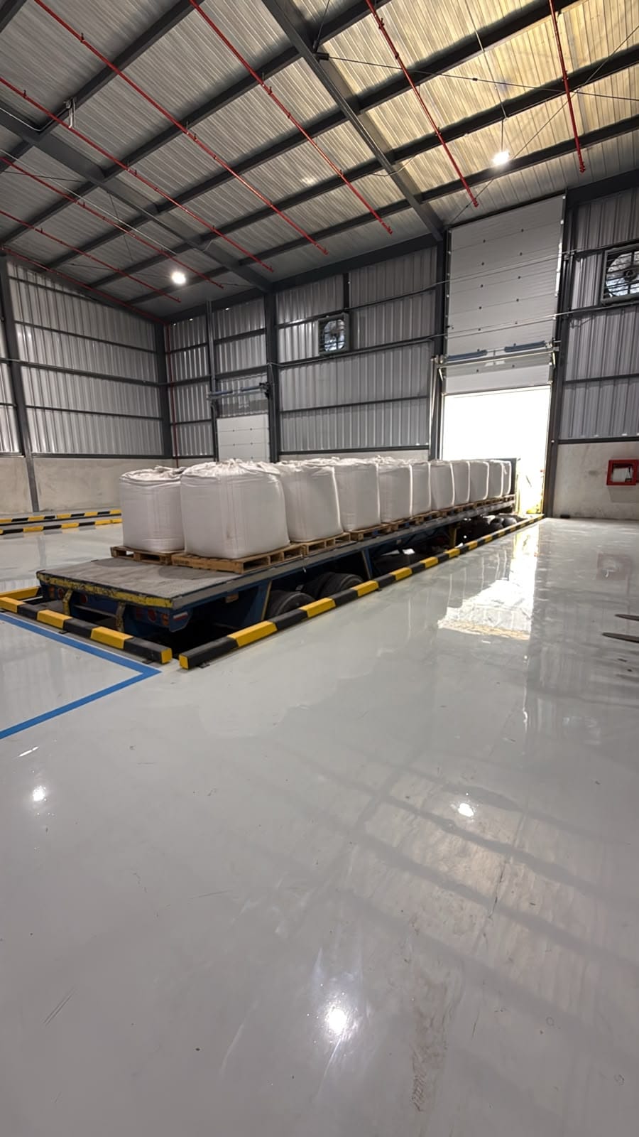 Flatbed trailer loaded with big bags being unloaded inside a Terminal Logístico Durán warehouse